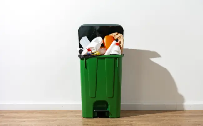 Green plastic rubbish bin filled with household waste